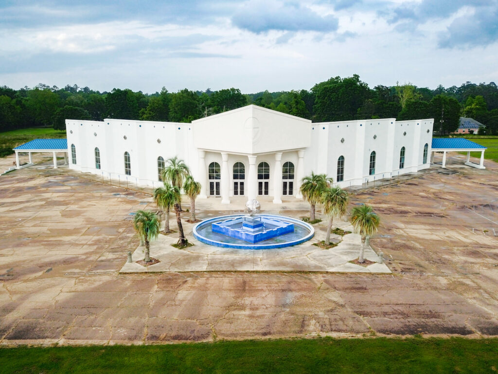 Front view of the I-12 Regional Church & Event Campus in Hammond, Louisiana featuring the ±45,820 SF main sanctuary building with prominent architectural design, large entryway, and ample paved parking – high-visibility commercial property with direct I-12 frontage.